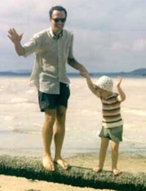 Bill and John Hunter standing on a log at the beach