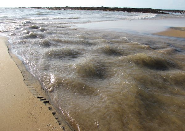 photo of rushing water joining the sea