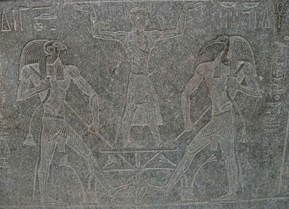 Egyptian carving of figures into a stone sarcophagus